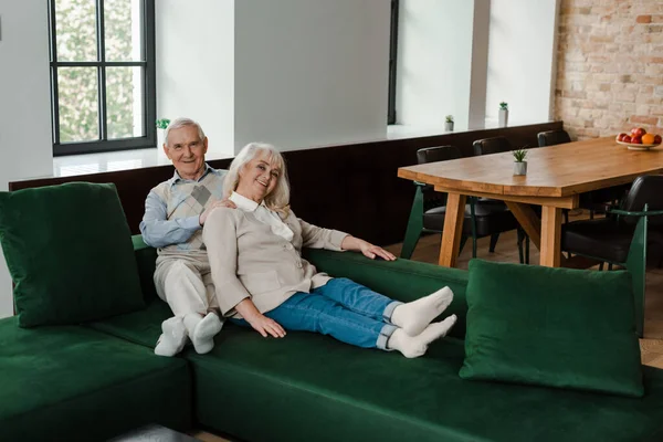 Улыбающаяся пожилая пара делает массаж и расслабляется на диване во время карантина — стоковое фото