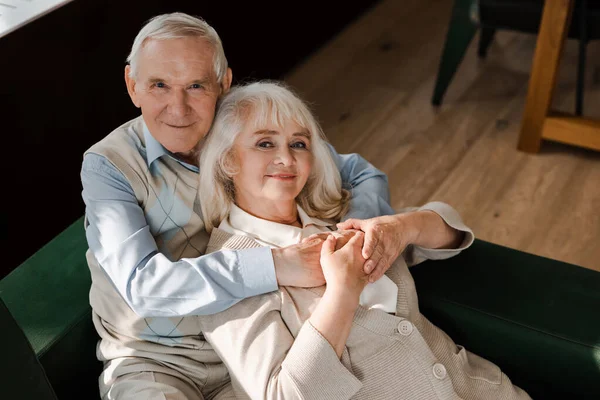 Улыбающаяся пожилая пара обнимается дома на карантине — стоковое фото