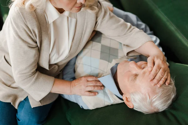 Vista recortada de la esposa anciana preocupada comprobar la temperatura del marido en casa en cuarentena - foto de stock