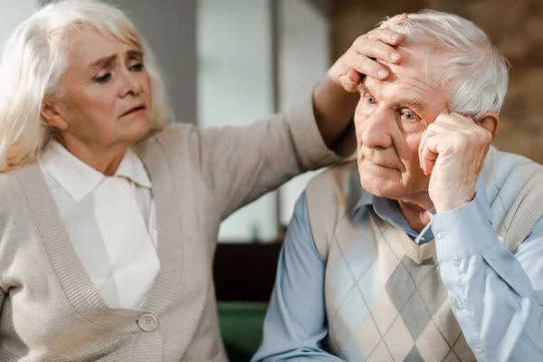 Worried elderly woman checking husband temperature at home on quarantine — Stock Photo