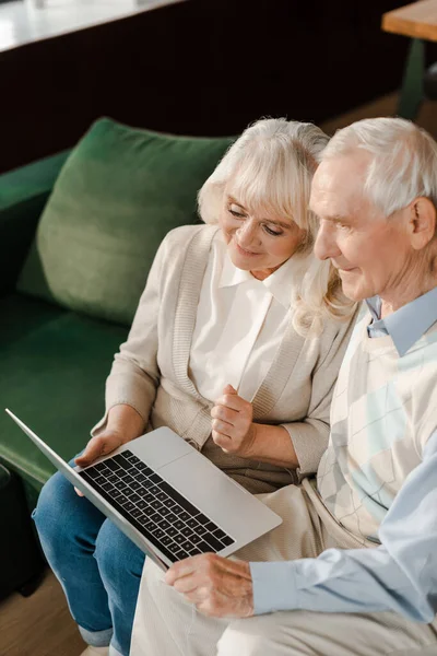 Lächelndes Senioren-Paar benutzt Laptop zu Hause während der Selbstisolierung — Stockfoto