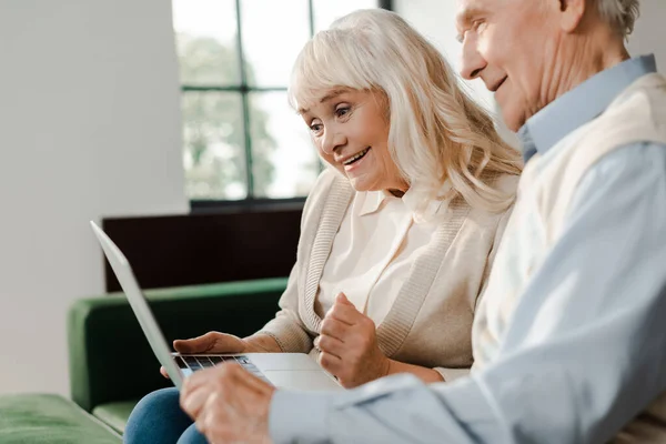 Lächelndes Senioren-Paar mit Videoanruf am Laptop zu Hause während der Selbstisolierung — Stockfoto