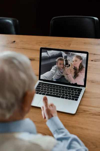 Cropped view of elderly man showing thumb up and having video chat with adult kids and dog during self isolation — Stock Photo