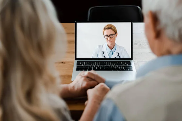 Älteres Paar hält Händchen, während es Video-Chat mit Ärztin in Quarantäne — Stockfoto