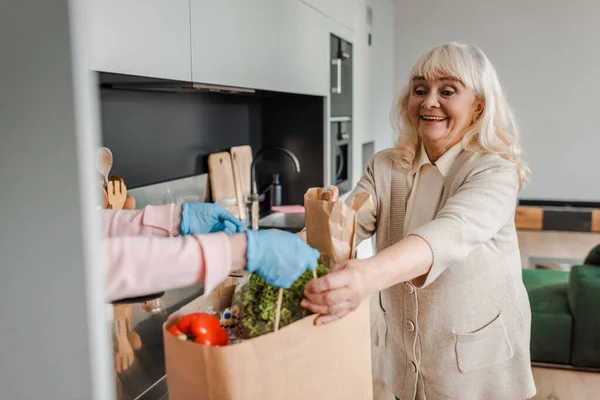 Happy elderly woman taking food delivery during coronavirus pandemic — Stock Photo