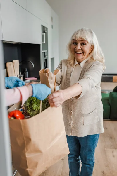 Happy elderly woman taking food delivery during coronavirus pandemic — Stock Photo