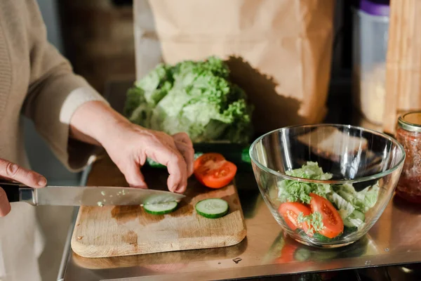 Vista cortada de legumes de corte de mulher sênior a bordo para salada na cozinha — Fotografia de Stock