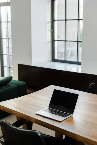 Laptop with blank screen standing on table at home with window — Stock Photo