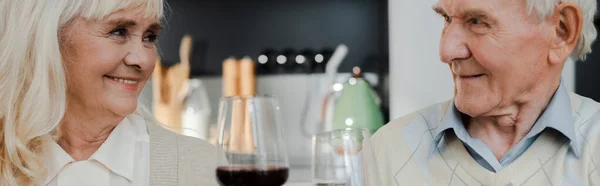 Счастливая пожилая пара пьет вино дома на самоизоляции, панорамная концепция — стоковое фото