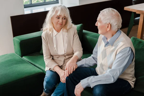 Trauriges Senioren-Paar hält sich in Selbstisolierung auf Sofa an den Händen — Stockfoto