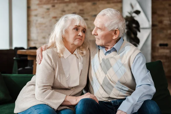 Triste couple de personnes âgées étreignant sur canapé pendant l'isolement personnel — Photo de stock