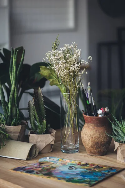 Green plants with art supplies on table — Stock Photo, Image
