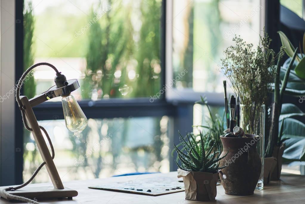 Green plants with art supplies on table