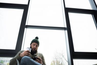 termos bardak ve smartphone tutan adam