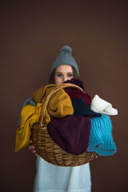 woman showing basket with hats and scarfs clipart