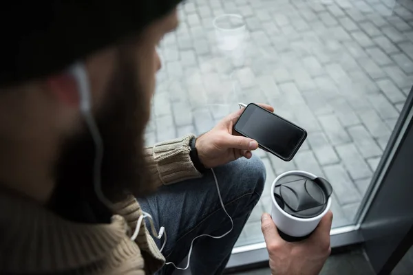 Hombre sosteniendo termo taza y teléfono inteligente — Foto de Stock