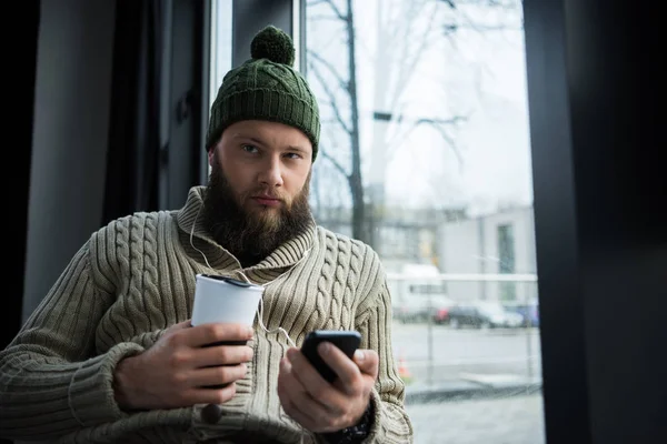 Man håller termosen cup och smartphone — Gratis stockfoto