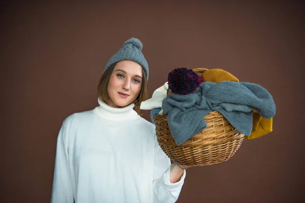 Женщина держит корзину с шляпами и шарфами — стоковое фото