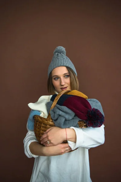 Woman holding basket with hats and scarfs — Stock Photo, Image