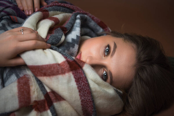 Woman lying on floor wrapped in blanket 