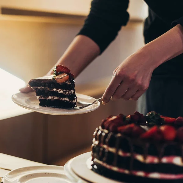 Mujer poniendo pedazo de pastel en el plato — Foto de Stock