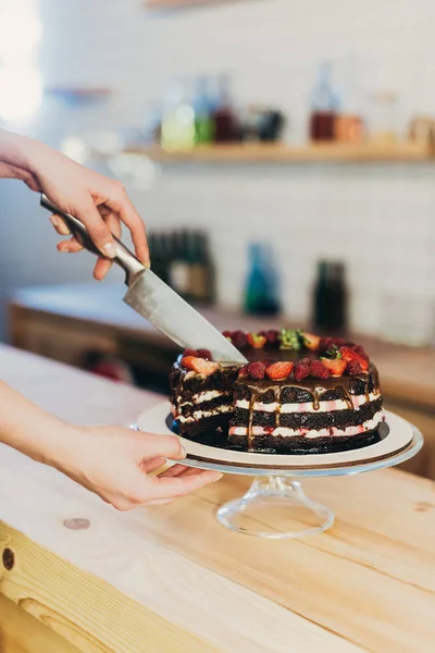 Mulher corte bolo de chocolate — Fotografia de Stock