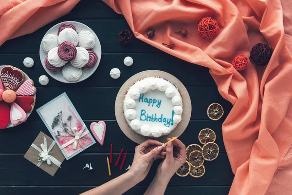 Woman putting candle on birthday cake — Stock Photo, Image