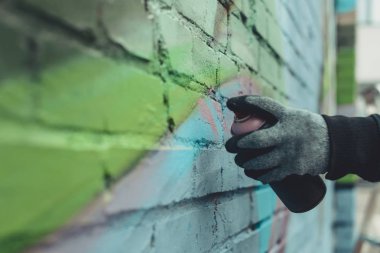 cropped view of man painting colorful graffiti on wall clipart