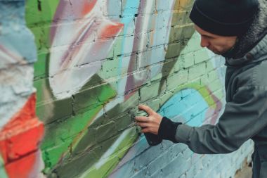 street artist painting colorful graffiti on wall clipart