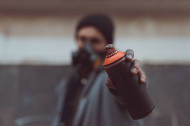 selective focus of street artist in respirator holding can with spray paint clipart