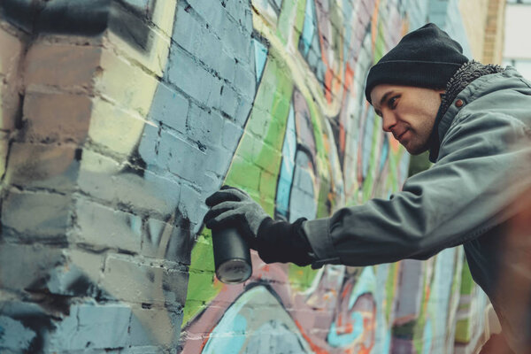 мужчина уличный художник рисует красочные граффити на стене
