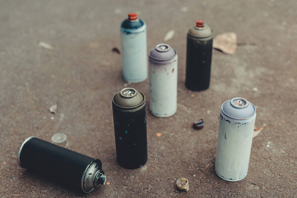 cans with colorful spray paint for graffiti on asphalt