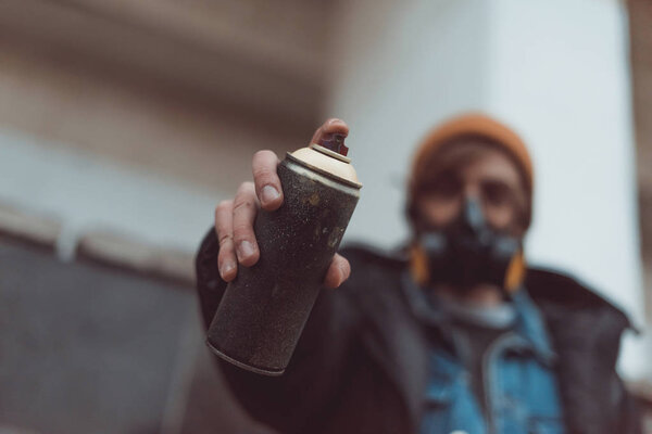 selective focus of street artist in respirator holding can with spray paint