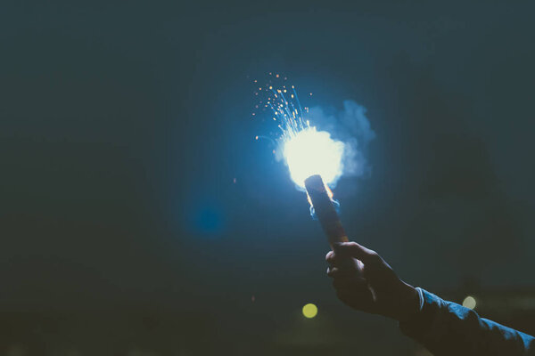 cropped view of male hand with smoke bomb at night