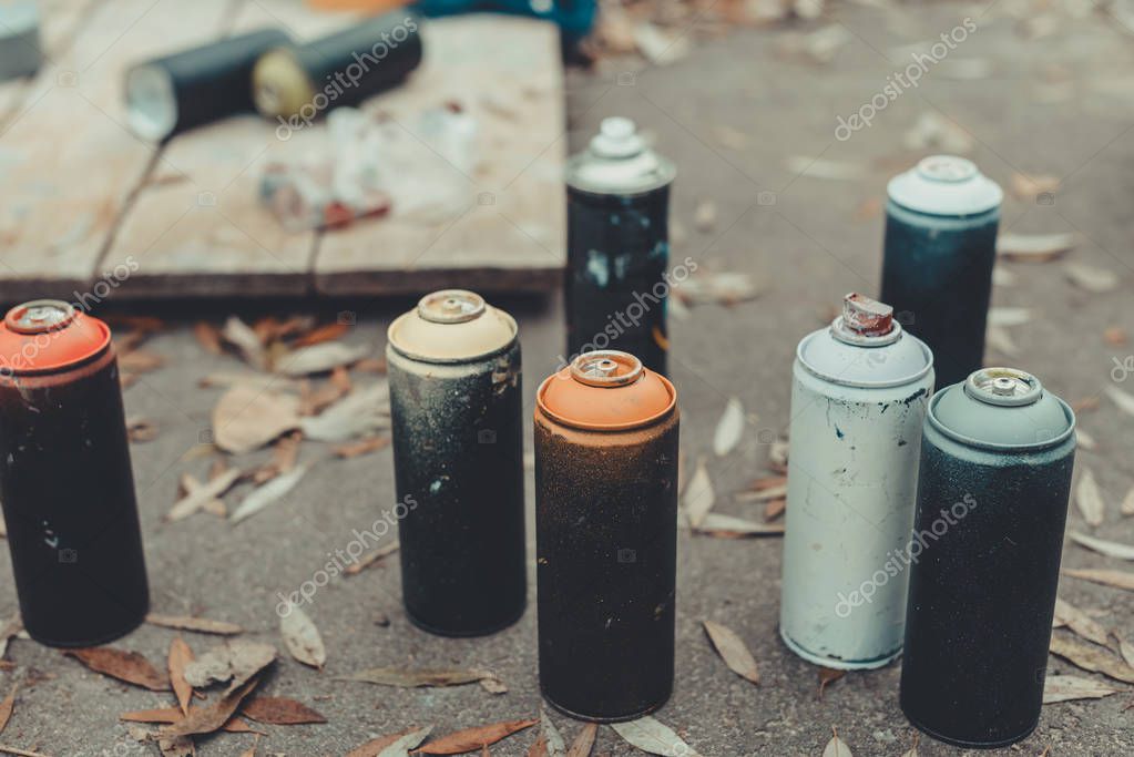 Cans with colorful spray paint for graffiti on asphalt