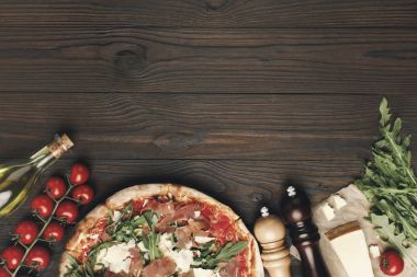 düz lay İtalyan pizza ve ahşap masa üzerinde çeşitli maddeler ile