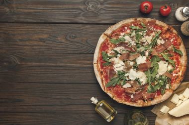ahşap yüzeyde görücü usulü ev yapımı İtalyan pizza, zeytin yağı, kiraz domates ve peynir Üstten Görünüm