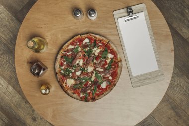 ahşap masa üzerinde İtalyan pizza, baharat ve yağı şişelerde türleri düzenlemenin Üstten Görünüm