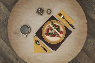 düz lay ile düzenlenmiş parça pizza plaka üzerinde fincan çay ve çatal bıçak takımı ahşap masa üzerinde