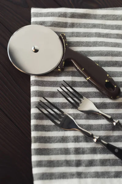 亚麻餐巾上的钢制叉子和比萨刀的关闭视图 — 图库照片
