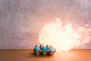 Painted eggs on fire on grey background clipart