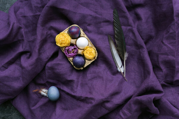 Пасхальные яйца и цветы в коробке на текстильном фоне

