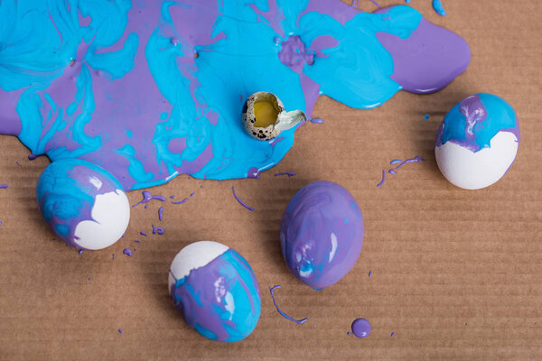 Разбитые перепелиные яйца и куриные яйца в краске на фоне картона
