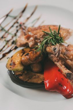 close-up view of tasty roasted chicken wings with grilled vegetables on plate  clipart
