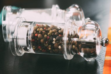 selective focus of salt and peppercorns in glass containers clipart