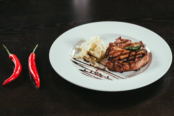 delicious grilled juicy steak with rosemary and chilli peppers on table