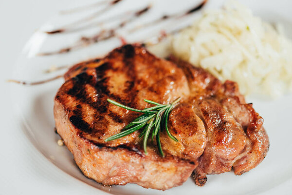 close-up view of fresh delicious grilled steak with rosemary on plate 
