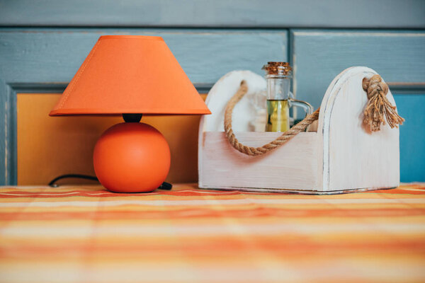 close-up view of decorative orange lamp and wooden box with spices on table in restaurant