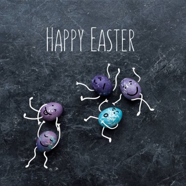 İle çizilen yüzler ve mutlu Paskalya yazı koyu arka plan üzerinde renkli Paskalya yumurtaları
