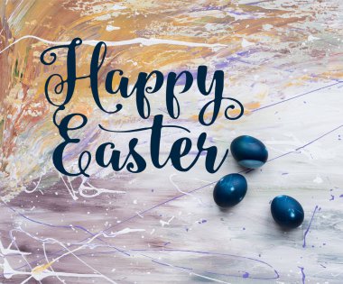 Painted Easter eggs with happy easter lettering on stained background clipart